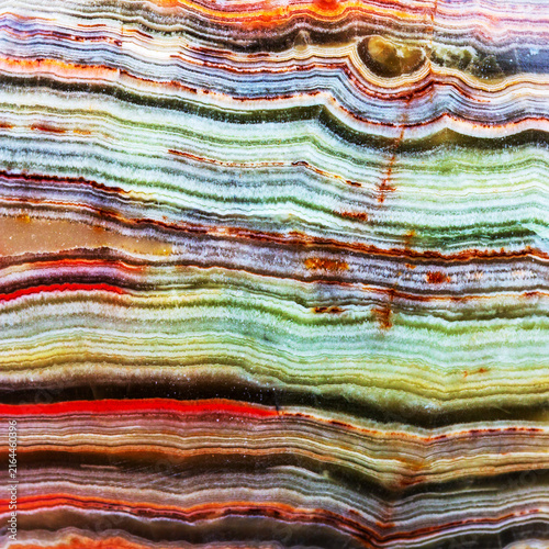 A close-up photo of a beautiful multicolored semiprecious agate stone, showcasing its intricate natural banding, vibrant hues, and glossy polished surface with unique geological patterns.