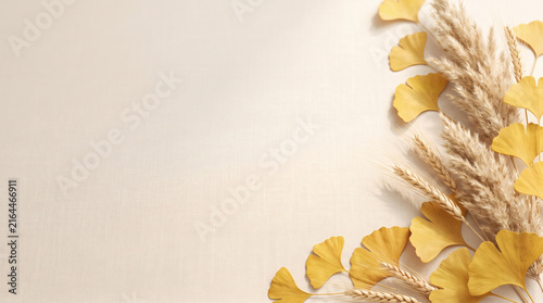 Autumn background with yellow ginkgo leaves pampas grass and wheat on beige linen texture with copy space