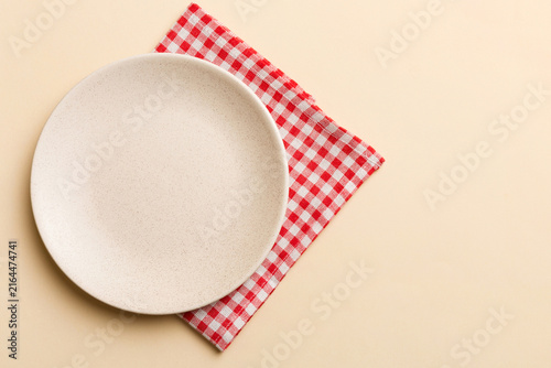 Top view on colored background empty round white plate on tablecloth for food. Empty dish on napkin with space for your design