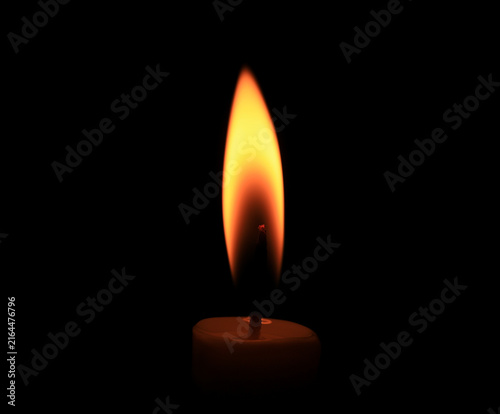 Candle flame glowing in darkness, isolated on a black background with warm orange light, creating a dramatic atmosphere for meditation, relaxation, spirituality, celebration, and moody visual design.