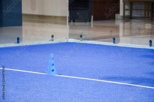 Blue marker cone on a synthetic turf court during a padel tennis ball training session