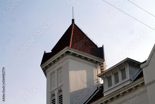 Historic White Building Tower With Red Tiled Roof Against Clear Sky, Architectural Detail And Shadows