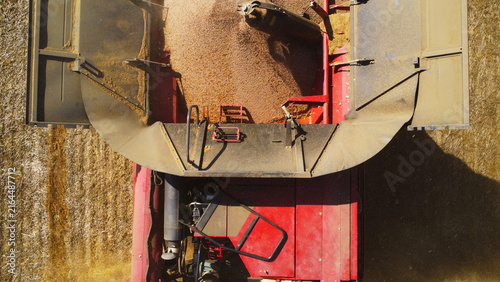 Foto A high-angle top-down aerial drone photograph offering a close-up perspective of a red combine harvester's grain hopper filling with freshly threshed grain