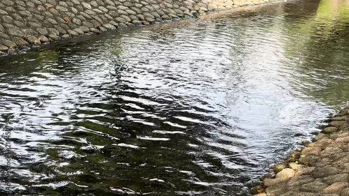 石垣に沿って穏やかに流れる小川の水面　心地よいせせらぎと光の反射が美しい自然の風景　プレゼンテーションの背景やヒーリング動画の導入素材として活用できる高精細なフルHDの背景ビデオ素材