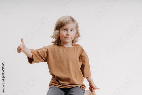 cute little boy in a black T-shirt is giving the thumbs up gesture