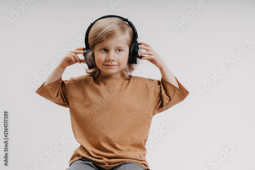 portrait of cute 4-5 year old boy with headphones on his head on white background
