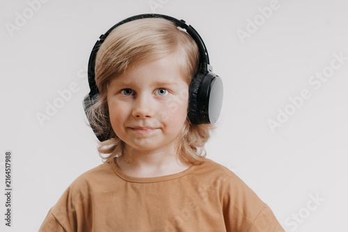 portrait of cute 4-5 year old boy with headphones on his head on white background