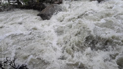 Powerful rapid glacial river with muddy white water cascading over rocks at Shkhara glacier in Svaneti region Georgia, fast flowing mountain stream, wild nature energy