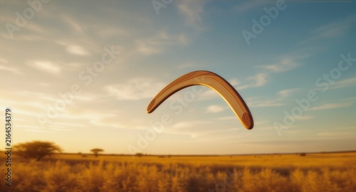 A classic wooden boomerang flying in mid-air above a golden savanna field during a warm sunset sky, showcasing themes of freedom, outdoor adventure, and traditional toys.
