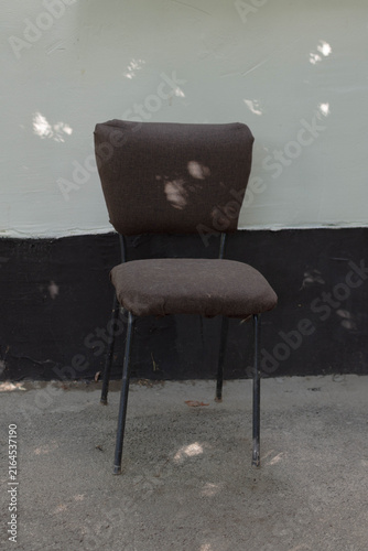 Photography A simple dark brown fabric chair with thin black metal legs, sitting outdoors ag