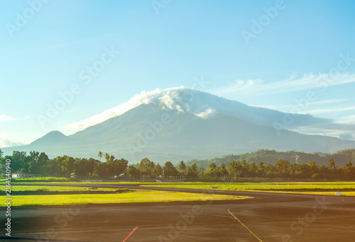 Breathtaking morning view of Mount Klabat topped with clouds, seen from the runway of Sam Ratulangi Airport in Manado, North Sulawesi, Indonesia.