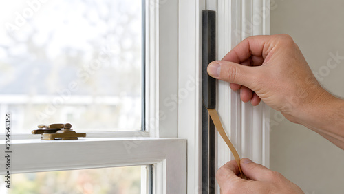 Hands Installing Foam Weatherstrip to Seal a Drafty Window