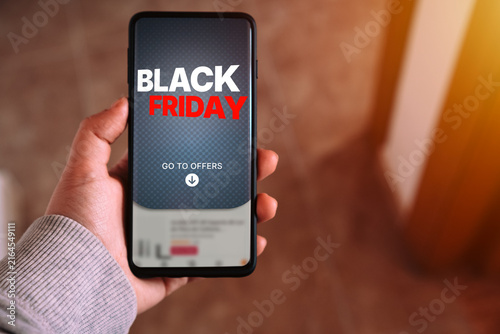 Black Friday sale offer on smartphone screen held by hand. Woman hand showing Black Friday offer on phone.