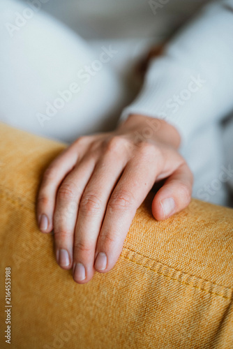 Quadro su tela Hand Resting on Yellow Couch Displaying Relaxation