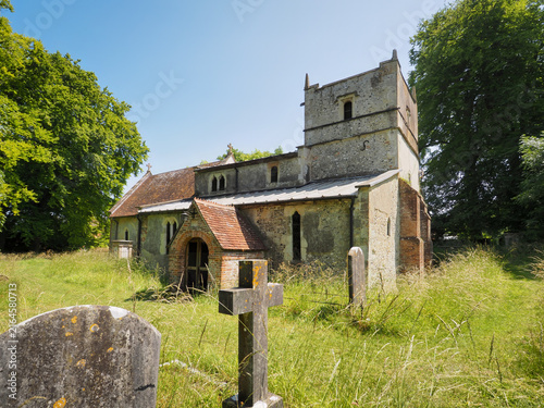Foto Historic 14th century St Michael's Church with its stone tower and sunlit grassy