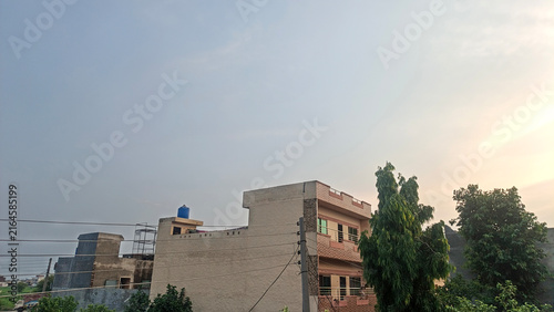 A row of houses under a vast sky with gentle sun rays touching the horizon creating a serene dusk atmosphere
