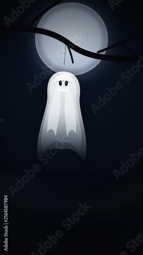 Fabric ghost decoration sways eerily from a tree branch in pale moonlight