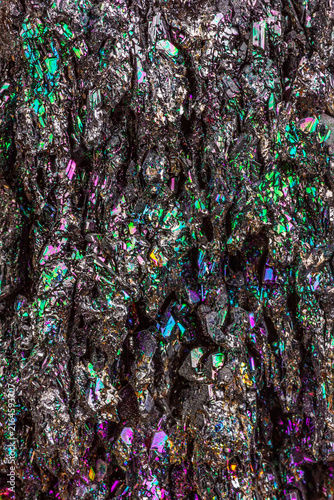 Macro close-up of a chalcopyrite stone, showcasing its metallic luster, iridescent tarnish, and multi color against a black background, revealing complex crystal texture and mineral details