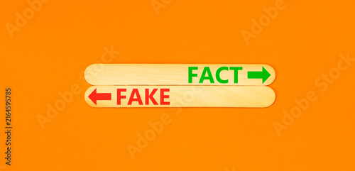 Fact or fake words symbol. Concept words Fake and Fact on beautiful wooden sticks. Beautiful orange background. Business and fact or fake concept. Copy space.