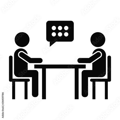 Two people sitting at a table talking in a meeting or discussion
