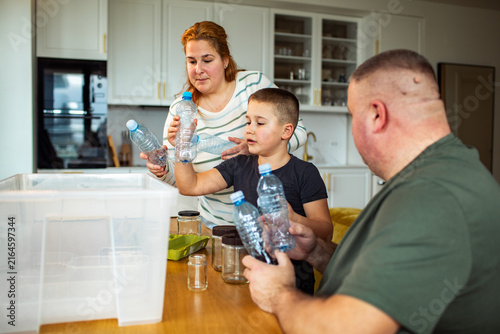 Family sorting plastic bottles for recycling at home kitchen