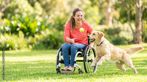Woman in wheelchair playing with dog outdoors as active disability and pet companionship concept
