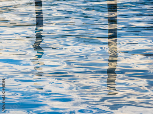 Close-up shot of lake water surface with reflection of pole
