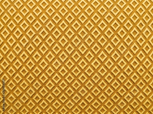 Textured golden yellow woven fabric featuring an intricate repeating geometric diamond pattern, ideal for upholstery or background design.