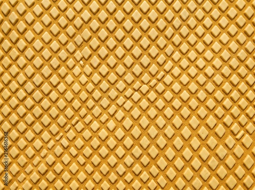 Textured golden yellow woven fabric featuring an intricate repeating geometric diamond pattern, ideal for upholstery or background design.