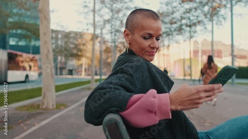 Happy Woman Using Smartphone on a City Street Bench