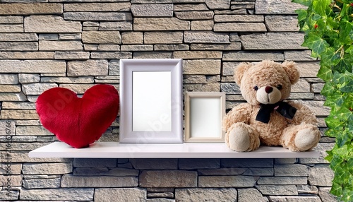 a white wall shelf displays a plush teddy bear heart decor and two blank photo frames against a textured stone wall with ivy