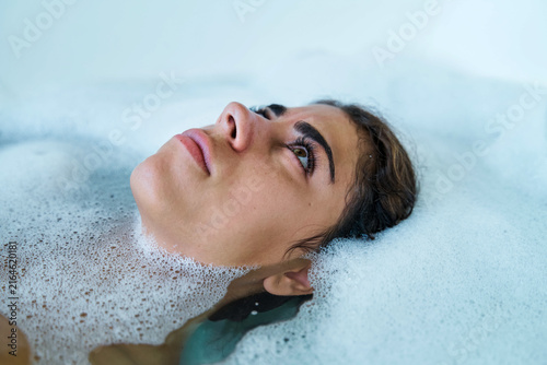 A white woman relaxes in a soothing bubble bath