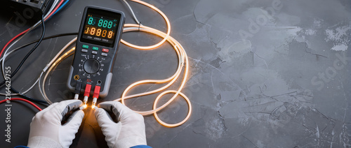Obraz na płótnie Digital multimeter fiber stream testing with glowing wire and gloved hands