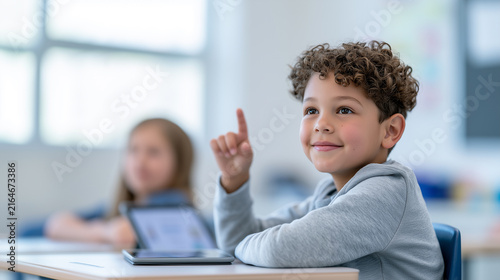 Portrait of a schoolboy in a modern classroom with a tablet on the desk.