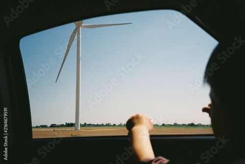 Unrecognizable child watching a wind turbine from a car