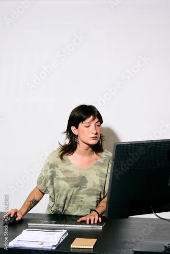 Businesswoman working at desk. A woman works at her desk with focused attention. She types on the keyboard while occasionally glancing at the monitor.