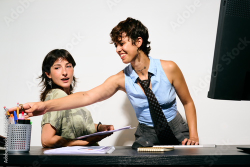 Two women collaborating at a desk. One points to a document while the other listens attentively. 