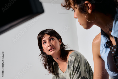Two women in a business office, one looking up at the other. One appears to be directing or advising the other,