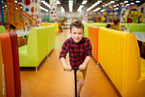 Photography Boy riding a green kick scooter indoors