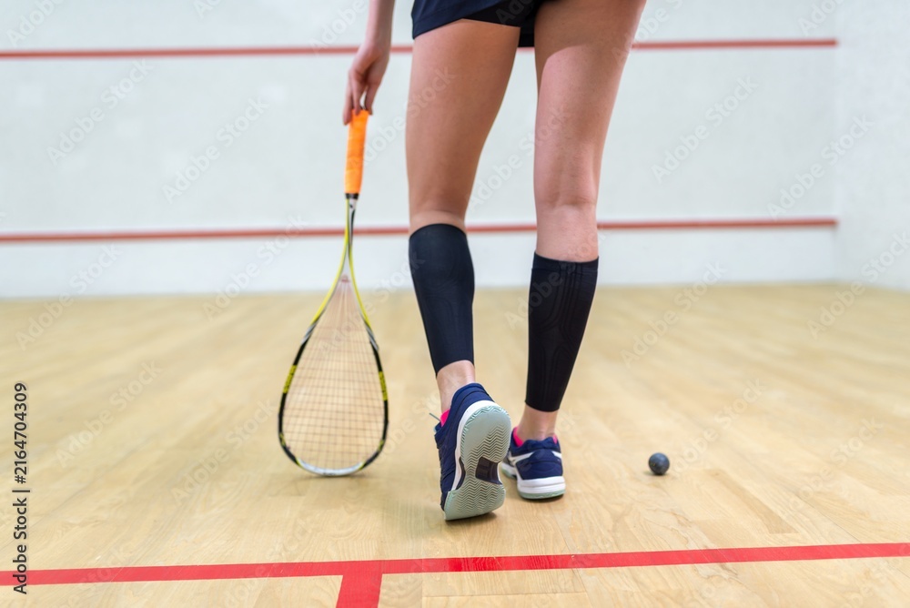 Fototapeta premium Legs of a female squash player with racket and ball