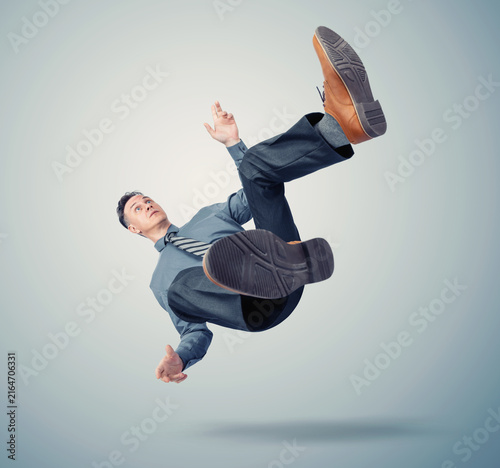 Businessman in shirt, trousers and tie falling through the air, symbolizing crisis, failure, risks, loss of control, financial trouble, career setback, uncertainty and sudden downfall chaos.