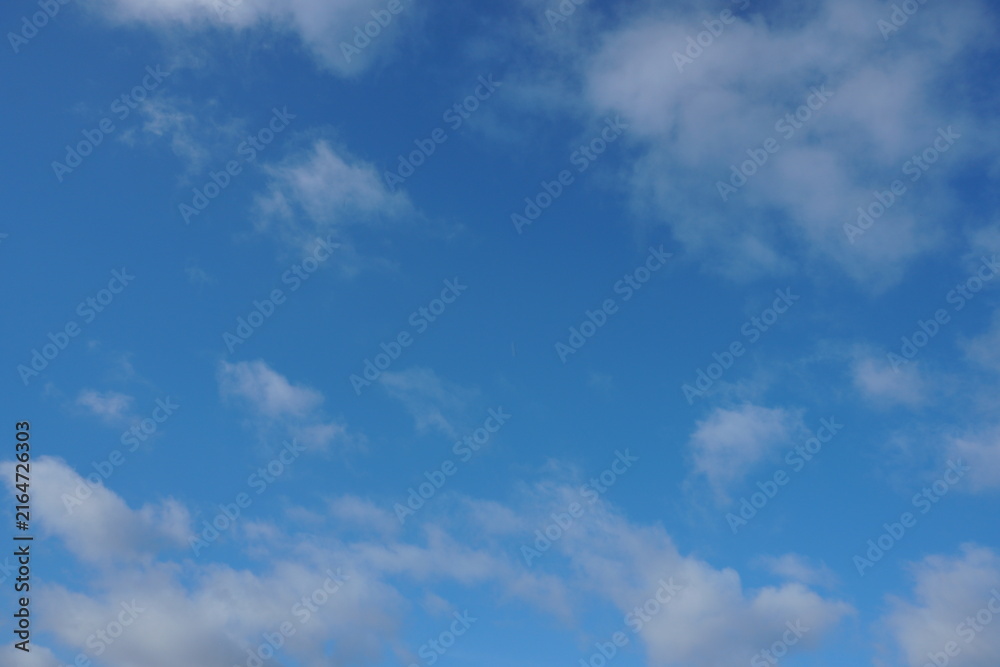 Obraz premium White fluffy clouds in the sky. Blue sky and cloud cover on a sunny summer day. Empty background, copy space