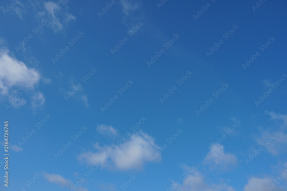 Obraz premium White fluffy clouds in the sky. Blue sky and cloud cover on a sunny summer day. Empty background, copy space