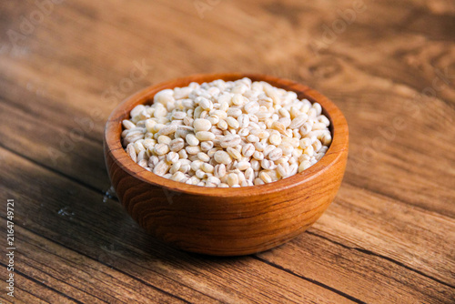 Obraz na płótnie Pearl barley in wooden bowl on wooden table