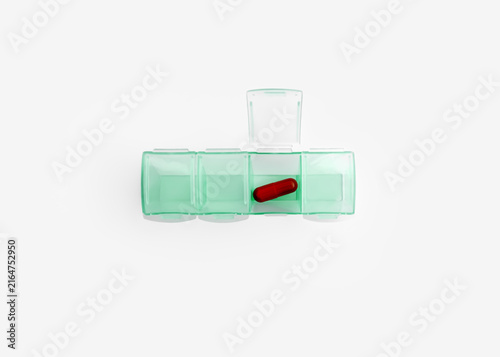 Green Plastic Pill Organizer with Red Capsule Isolated