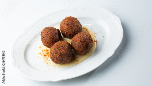 Bild auf Leinwand Gourmet cheese-stuffed herb croquettes with creamy sauce on a white oval plate