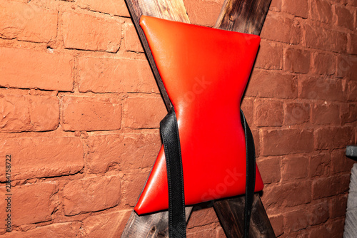Red cushioned restraint leans against rustic brick wall