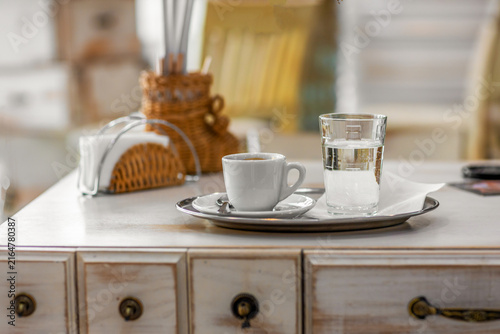 Cup of espresso with a glass of water on a tray in a cafe
