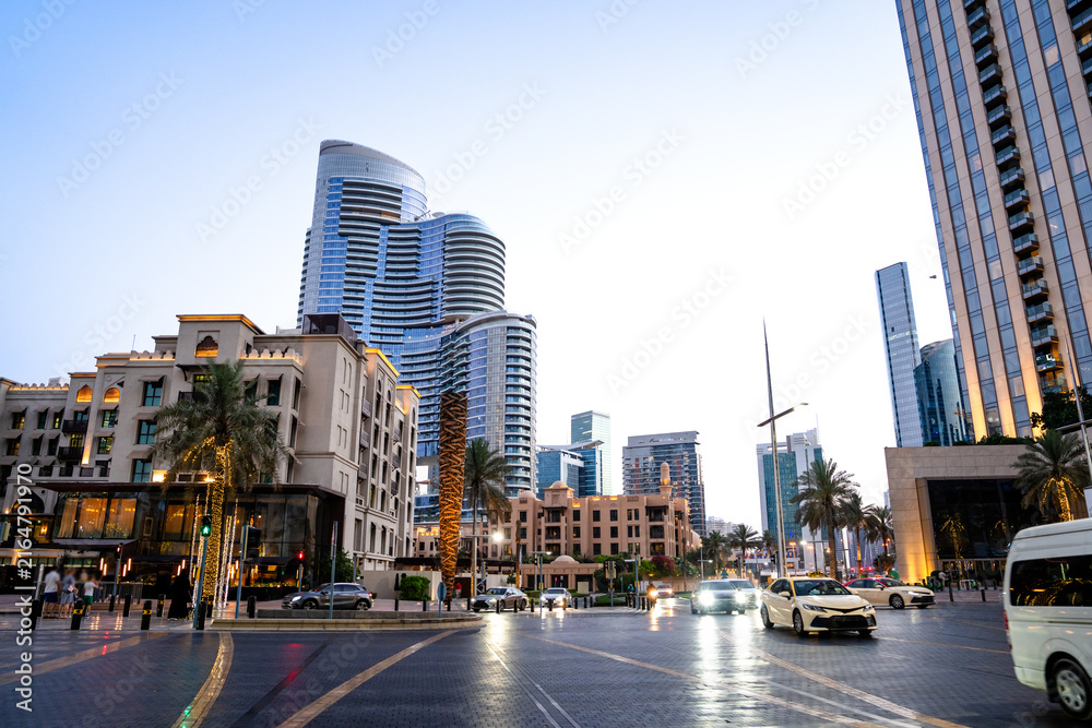 Obraz premium At sunset, a busy city with skyscrapers, cars, and people