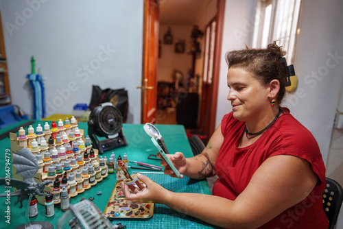 Fotografie Woman painting miniature figurine at home workspace, focusing on detailed hobby